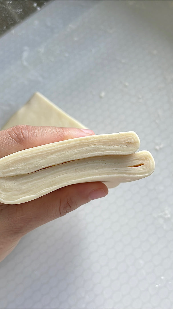 Laminated croissant dough held in hand, customer photo from a Shopee review
